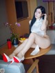 A woman sitting on top of a table next to a bowl of fruit.