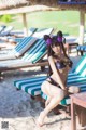 A woman in a bikini sitting on a beach.