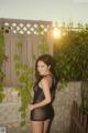 A woman in a black dress standing in front of a fence.