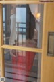 A woman standing in front of a glass door.