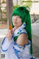 A woman with green hair holding a leaf in her hand.