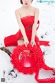 A woman in a red dress sitting in the snow.