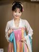 A woman in a pink and blue hanbok is posing for a picture.