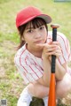 A young girl in a baseball uniform holding a baseball bat.