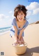 A woman sitting on a beach with a basket of food.