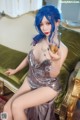 A woman with blue hair sitting on a green couch holding a glass of wine.