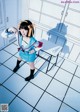 A woman in a school uniform standing in front of lockers.