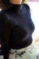 A woman wearing a black turtleneck sweater and a floral skirt.