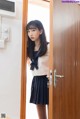 A woman in a school uniform standing in front of a door.