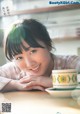 A woman sitting at a table with a cup of coffee.