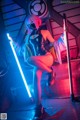 A woman in a latex outfit holding a light saber.