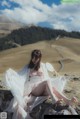 A woman sitting on top of a rock holding a mirror.