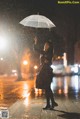 A woman holding an umbrella in the rain at night.