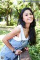 A woman leaning against a brick wall in a park.