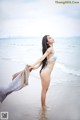 A woman in a white bikini standing on a beach.