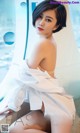 A woman in a white dress sitting on a window sill.